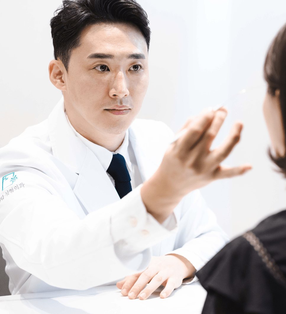 흰 가운의 원장이 환자의 얼굴을 보며 상담하는 모습